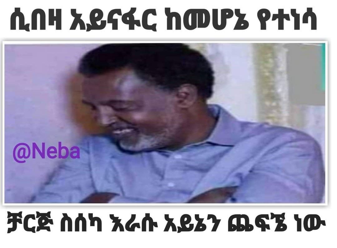 a man in a blue shirt is smiling and holding a cell